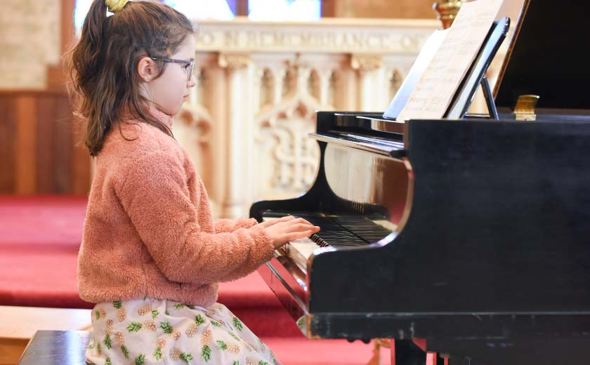young girl playing the piano in a concert performance